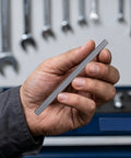 Hand holding a 5mm x 100mm stainless steel shaft rod intended for RC car axle replacement.