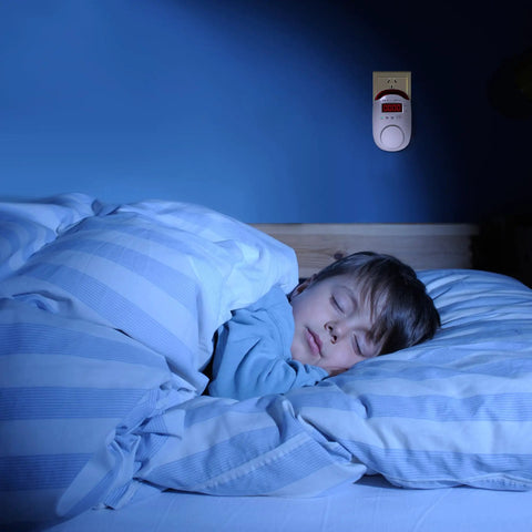 Child sleeping peacefully with a Two Pack Plug In Gas And Carbon Monoxide Detectors With LCD Display visible on the wall in a bedroom.