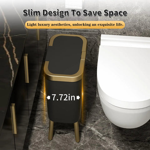 Slim black trash can with lid and gold edge in bathroom next to toilet, space-saving design, modern narrow trash bin on legs