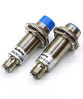 Motion Inductive Proximity Sensor With M12 Connector, Durable 18mm FRCM18-5DO Style Sensor For Industrial Automation, Ideal For Robotic Arms, Conveyors, And Machines, High-Precision Sensing, Plug And Play, two metal sensors on white background