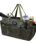 Army green waxed canvas firewood carrier tote filled with garden tools and utensils, showing collapsible and sturdy design.