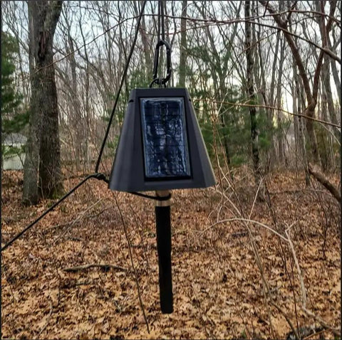 Heavy Duty Solar Hanging Enclosure For LoRa Nodes, mounted in the woods, featuring a solar panel and secure fit for batteries.