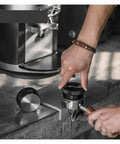 Adjustable Height Espresso Coffee Distributor Tool For Flawlessly Even Coffee Beds being used with portafilter on a countertop.
