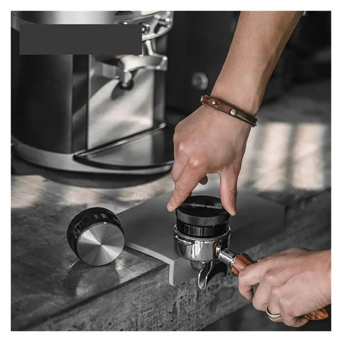 Adjustable Height Espresso Coffee Distributor Tool For Flawlessly Even Coffee Beds being used with portafilter on a countertop.