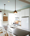 Modern kitchen interior with pendant lights above island, white cabinets, and high chairs