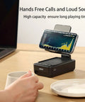 Phone Stand With Bluetooth Speaker And LED Color Changing Light on desk holding smartphone, coffee cup nearby