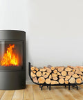 Curved Firewood Rack, 48-Inch Heavy Duty Log Holder For Indoor And Outdoor Use next to a lit fireplace, black metal design.
