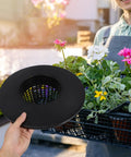 Person holding durable hydroponic mesh net pot bucket with high drainage in a garden setup with colorful flowers