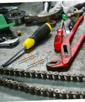 Door Hinge Repair Kit Pin And Bushing For Automotive Door Hardware with tools on a workbench, including pliers and screwdrivers.