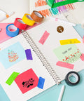 Open creative journal with Rainbow Masking Tape Set With Twelve Rolls Of Colorful Painter Tape One Inch By Seven Hundred Twenty Feet Each, vibrant craft tape decorating the pages.