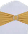 Front view of a gold spandex chair sash with a rhinestone ring centerpiece on a white banquet chair cover