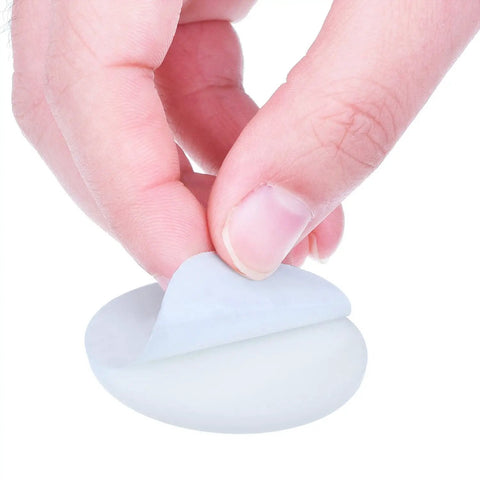 Close-up of a hand peeling the adhesive backing from a white 20 Pack Self Adhesive Door Knob Wall Protector Round Rubber Bumper