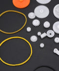 Assorted plastic gears and bands from 78 Piece Gear Kit For DIY RC Cars And Robots Module 0.5 Small Gears With Axles Tires And Bushings