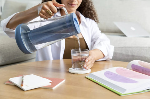 Person pouring water from Water Filter Pitcher 7 Cup Glass With Silicone Base Stormy Blue Removes Bacteria Parasites Microplastics Lead Mercury PFAS And A Range Of Chemicals For Everyday Tap Water Protection into glass
