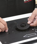 Hands adjusting the plate on the Rock Solid Free Standing Router Table With Heavy Duty Steel Base And Spacious 24 By 16 Inch Laminated Top.