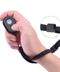 Wireless Phone Camera Remote Shutter Two Pack For iPhone And Android Hands Free Selfie Button With Wrist Strap shown in hand