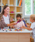 Children and teacher using 122 Piece Magnetic Science Kit For Kids with colorful chips, magnetic balls, wands, and magnets.