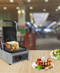 Heavy Duty 1800W Commercial Sandwich Panini Press Grill with sandwich, stainless steel, in a restaurant setting.