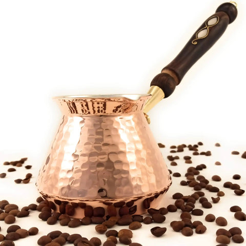 Hand Hammered Copper Turkish Greek Arabic Armenian Coffee Pot Large 18 Fl Oz Stovetop Cezve Jazzve Ibrik Briki Heavy Duty Coffee Maker For Loads Of Flavor Turkish Coffee Classic Hammered Design with wooden handle and coffee beans.