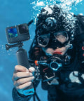 Diver holds Floating GoPro Hand Grip Accessory Floaty Stick Waterproof Handle for GoPro Hero with blue cap underwater.