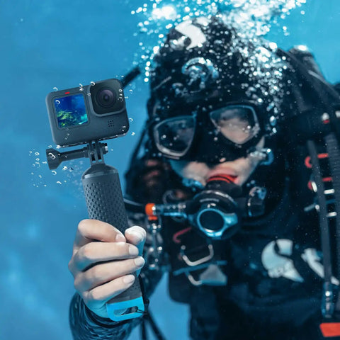 Diver holds Floating GoPro Hand Grip Accessory Floaty Stick Waterproof Handle for GoPro Hero with blue cap underwater.