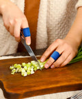 Person wearing 100 Pcs Blue Bandages 3 By 1 Inch Metal Detectable Waterproof PE Adhesive Bandages For Food Handling And Kitchen Use slicing vegetables