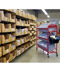 Heavy Duty Red Tote Picking Cart For Warehouse Retail And Office Order Fulfillment With Angled Shelves That Lock In Nine Bins setup near cardboard storage boxes.