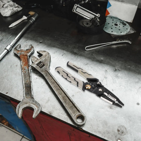 Pretyzoom 7-In-1 Cable Stripper And Crimper For Electricians on a metallic workbench with wrenches.