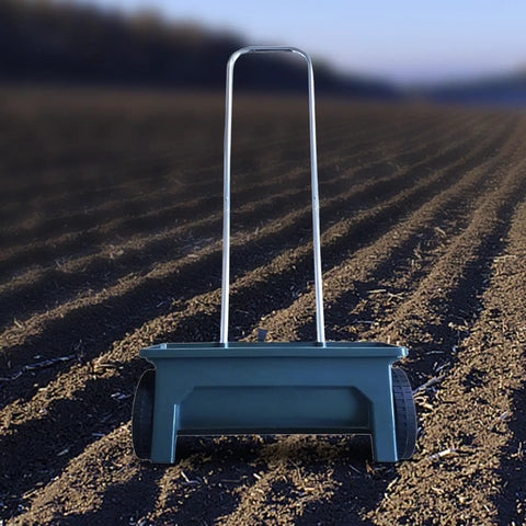 Walk Behind Seed Spreader 12 Liter Hand Push Garden Seeder Broadcast and Drop Spreader on plowed field background