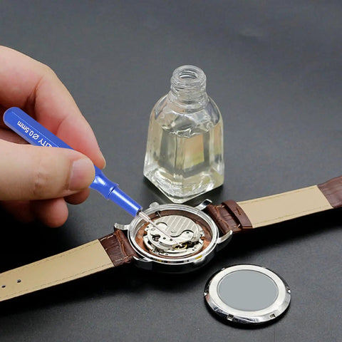 Pro Grade Watch Oil Pen Tool for Precision Lubrication used on a mechanical watch, blue aluminum handle, bottle of oil nearby