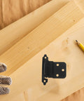 No Fuss Soft Closing Cabinet Hinge With Built In Spring Self Closing Door Closer on wooden board beside gloved hand and pencil