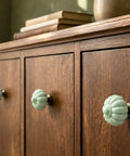 Fresh Vintage Light Green Ceramic Pumpkin Drawer Knobs And Cabinet Pulls displayed on a wooden cabinet with books.