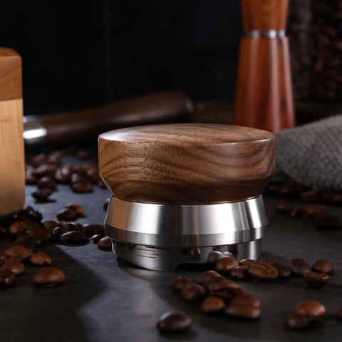 58.5mm Coffee Distributor with Walnut Wood Handle and Stainless Steel Base among coffee beans on countertop