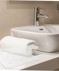 Wall Mounted Spray Bottle Holder Knocks The Mess Out Of Your Bathroom Or Garage With Heavy Duty Acrylic Design displayed next to a rolled towel.