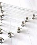 Assorted sizes of sleek Lucite acrylic cabinet pulls in clear chrome finish displayed on a surface, polished silver handles.