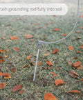 Grounding rod stake with gray 40 ft conductive cord on grassy lawn with autumn leaves