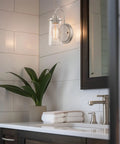 Kira Home Rayne 10" Modern Farmhouse Wall Sconce for Bathroom Vanity, Pack of 2 illuminating a bathroom with clear glass shade.