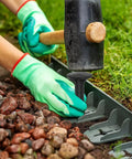 Person using mallet to install 80 Pack Plastic Lawn Stakes Six Inch Ground Anchors Spikes Heavy Duty For Lawn Edging Weed Fabric Tarp