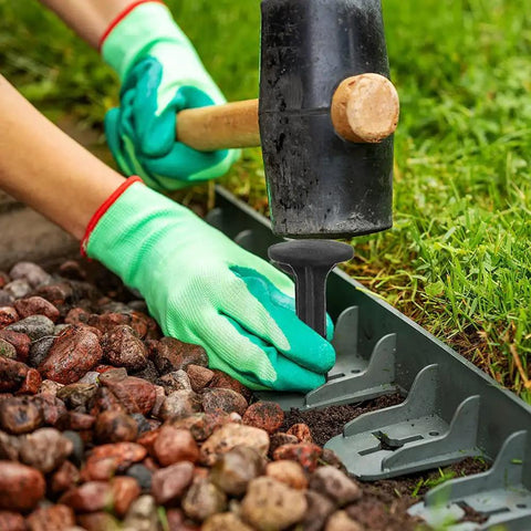Person using mallet to install 80 Pack Plastic Lawn Stakes Six Inch Ground Anchors Spikes Heavy Duty For Lawn Edging Weed Fabric Tarp