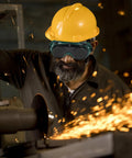 Job Site Tough Flip Up Welding Safety Glasses With Vented Anti Fog Shell Double Layer Shatterproof Lenses For Stick Mig Argon Cuts And Everyday Shop Grinds 2 Pack worn by worker with a yellow hard hat.
