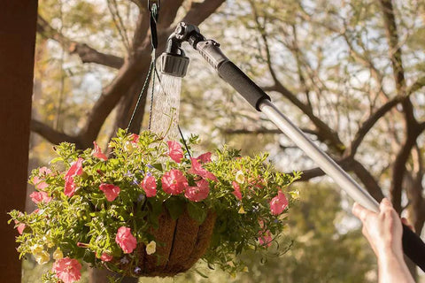 Person using 2-Pack Telescoping Watering Tool With Five-Position Pole Extending From 3.5 To 6 Feet, Four Spray Patterns Including Vertical, Horizontal, Jet, And Shower, Locking Pivot Head For Easy Angling to water hanging flowers