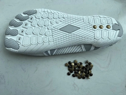 Zureto copper grounding rivets for barefoot shoes; pile of small copper rivets beside a white/gray shoe sole.