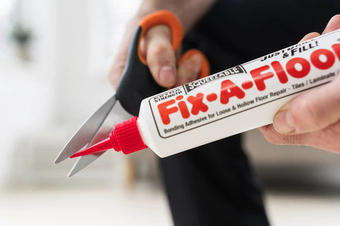 All In One Floor Repair Adhesive For Loose Hollow Tiles And Creaky Wood From A Simple Squeeze Tube With Precision Tip Drill And Fill No Mess Easy To Use For DIY And Pro Grade Installations Made In The USA Fix Floors Fast And Durable tube close-up with scissors opening spout