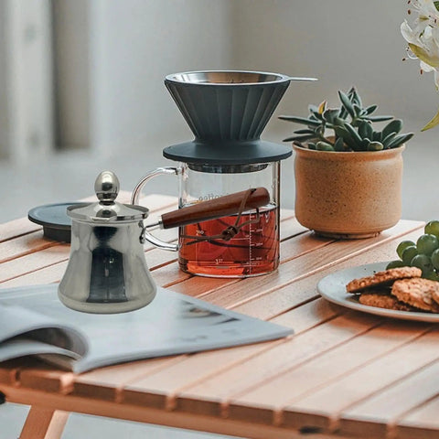Stainless Steel Coffee Pot With Lid And Wooden Handle For Stovetop Brew Milk Warmer And Butter Melter 250ml Pour Spout Induction Compatible Cafe Essential on a table next to a coffee dripper and plant.