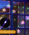 Color Changing Star Window Christmas Lights With 9 Star Curtain Ornaments Multicolor And Warm White Battery Operated With Timer 8 Modes IP65 Waterproof Xmas Window Decor For Indoor And Outdoor Use displayed on window at night.