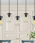 Five Light Mason Jar Pendant Lighting Fixture Black Rustic Farmhouse Chandelier For Kitchen Island, Dining Room, Hallway, Foyer, Living Room, And Bedroom With Adjustable Height Glass Jar Shades Cozy Vibe, hanging in a modern kitchen setting.
