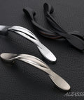 Three twisted arch cabinet pulls in brushed satin nickel, silver, and black on textured surface, showing design for 10 Pack Brushed Satin Nickel Cabinet Pulls With 3 Inch Hole Centers Arch Twisted Design For Cabinets And Drawers Kitchen Furniture Hardware AL3027SN High Quality Solid Construction For Everyday Use.