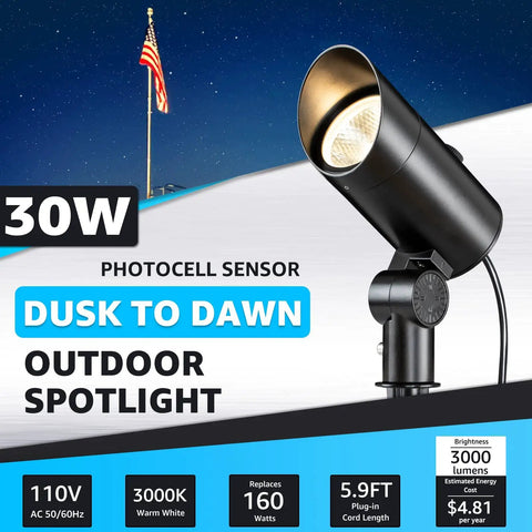 Dusk To Dawn 30W Outdoor LED Spotlight With Photocell Sensor illuminating a flagpole, 3000K warm white, black stake mount design