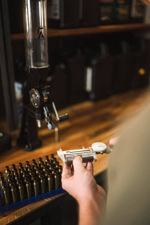 Person using Bench Top Powder Measure With Improved Funnel Shape And Static Free Aluminum Body For Accurate Ammunition Reloading Micrometer Adjustable Charge From 10 To 100 Grains Black at reloading bench.
