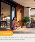 Person sitting on a porch using remote with Eolis 3D WireFree RTS Wind Sensor For Awnings, off white finish in home setting.